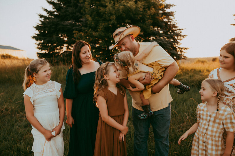 Family of seven playing in a field at sunset wearing their sunday best.