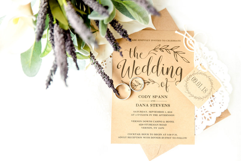 A wedding invitation with the couple's rings and sprigs of lavender.