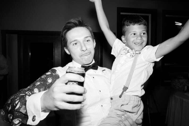Groom holds a beer in one hand and his celebrating nephew in the other