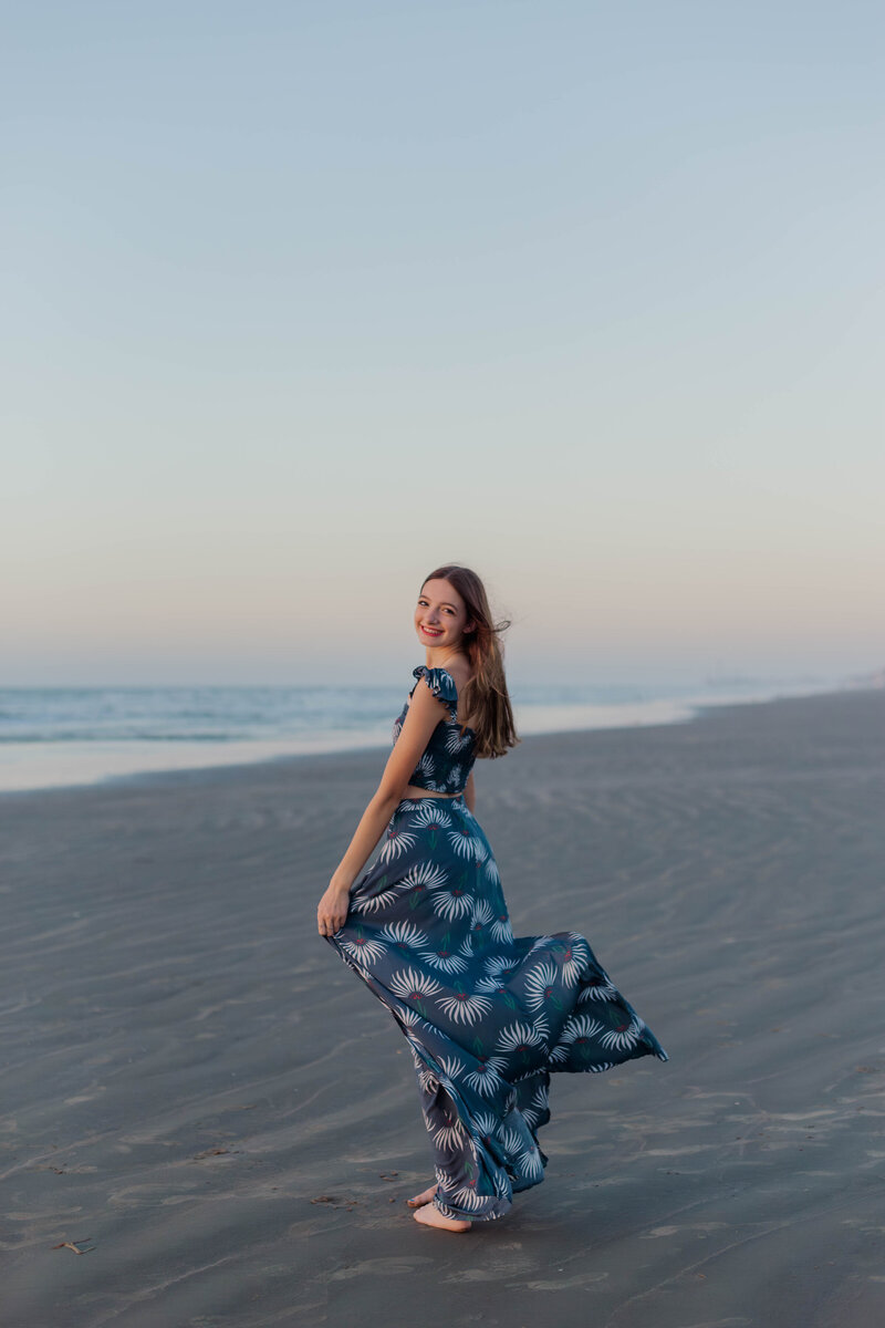 Young girl with a navy blue dress blowing in the wind on Galveston Beach