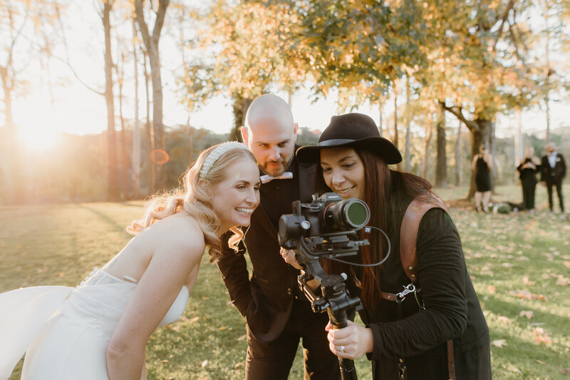 A photo of Tashina Narelle showing the back of a camera to the bride and groom. Auckland wedding photographer and videographer
