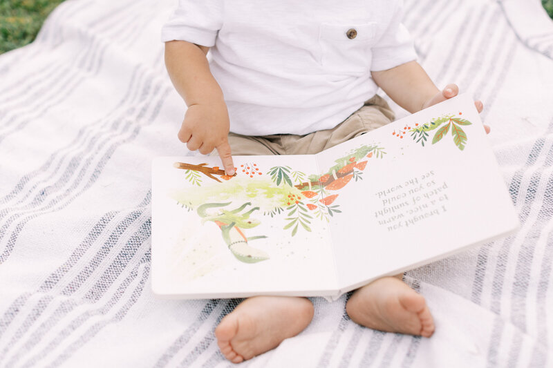 Details of a toddler looking at a book on a blanket