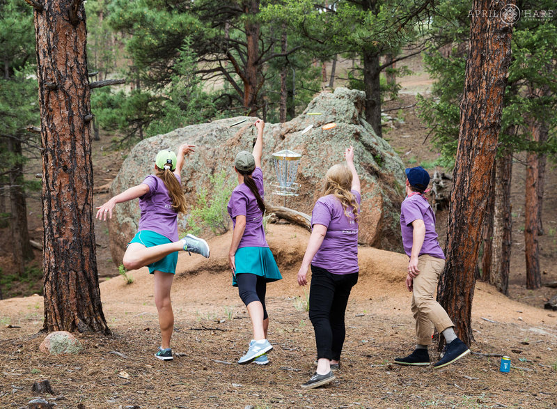 Group of friends in matching outfits play a round of disc golf on their wedding day at Bucksnort Disc Golf in Colorado