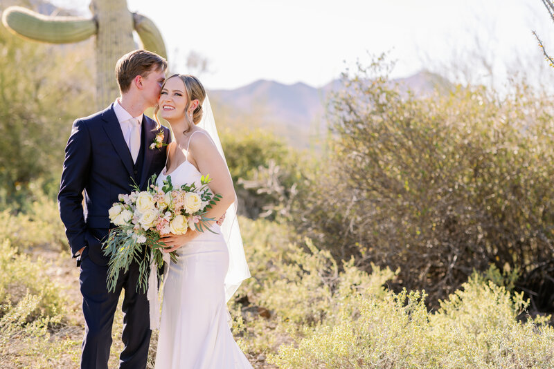 Couple pose in front of a saguaro cactus on wedding day in Tucson