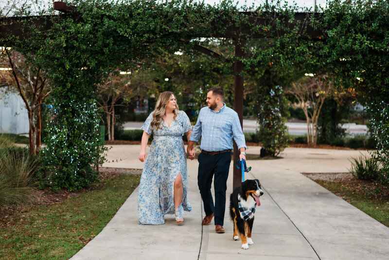 SPRING ENGAGEMENT SESSION IN GAINESVILLE, FLORIDA. A COUPLE WITH THEIR DOG WALKING IN A PARK.