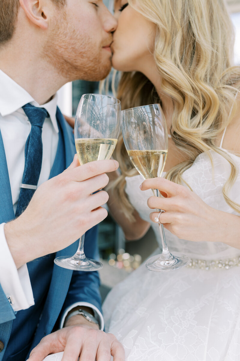 Detail photo of a couple kissing as they hold champagne glasses at Lytle Park Hotel.