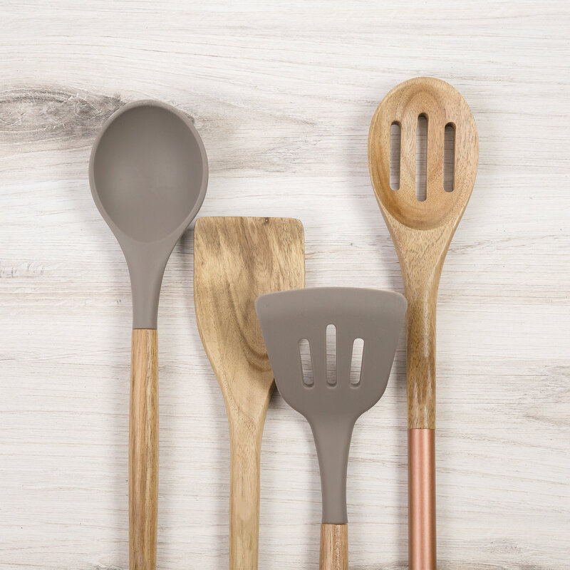 wooden spoons and wooden spatulas sitting on marble counter