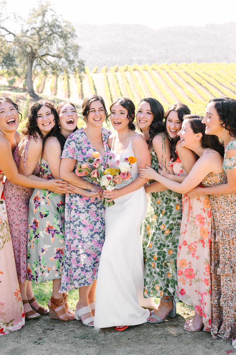 bride with bridesmaids in assorted floral gowns in a northern california vineyard.
