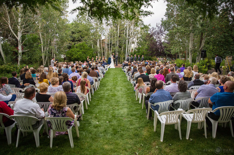 Wedding guests sit in white chairs on the lawn outdoors at Church Ranch Event Center