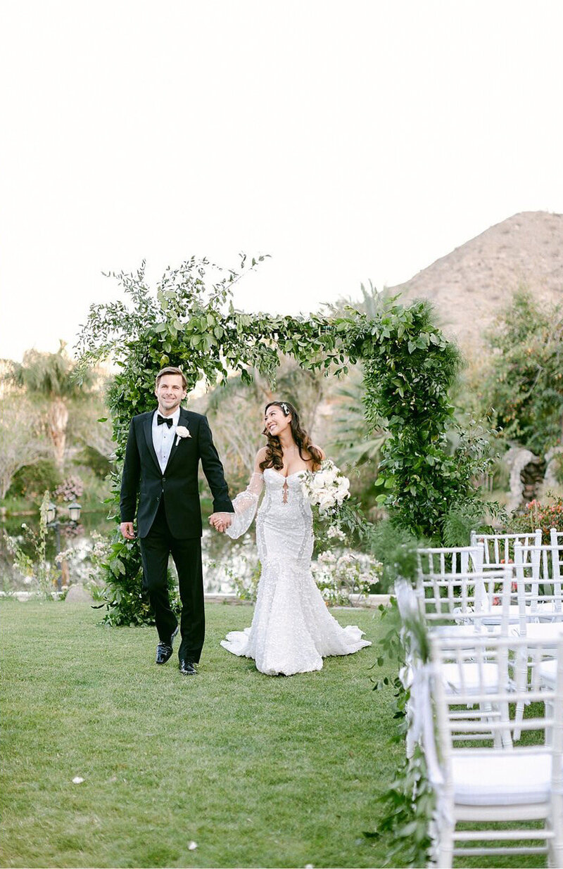 Elegant modern bride and groom walk back down the aisle after their wedding ceremony