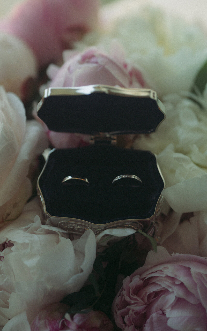 Beautiful engagement or wedding rings delicately placed on peonies, symbolizing love and elegance, surrounded by soft floral beauty for a romantic touch