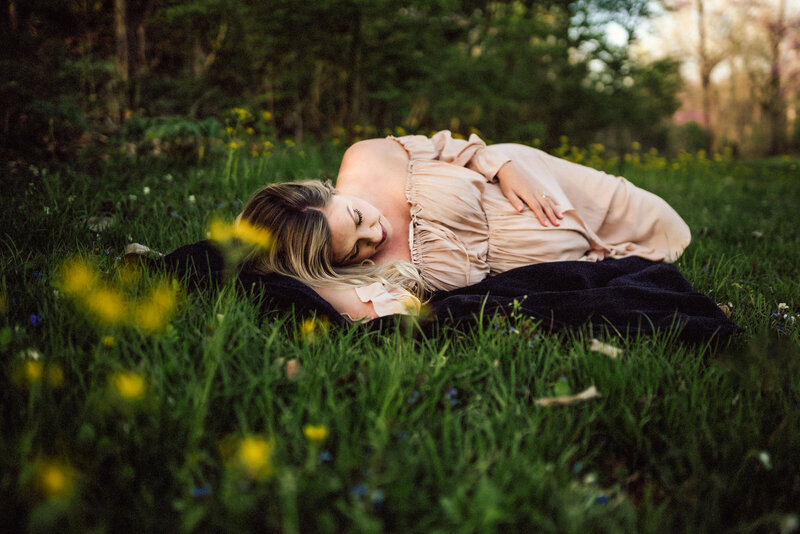 Pregnant woman lying in grass with yellow flowers