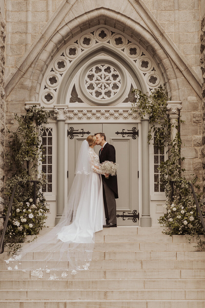 Couple's church steps kiss, wedding photo.