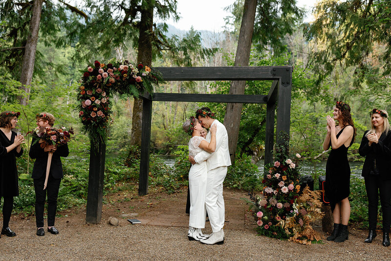 Couple embracing under arbor at outdoor wedding