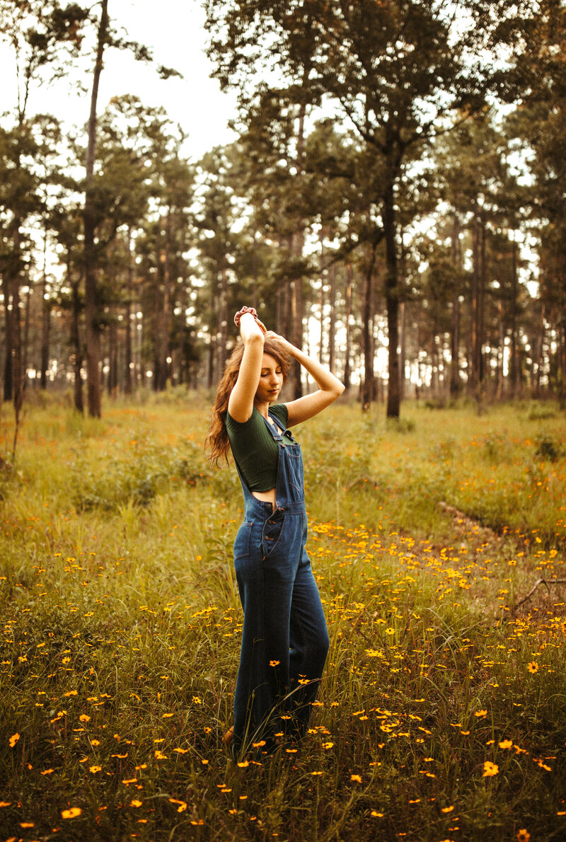 woman standing in field of wild flowers with trees in the background