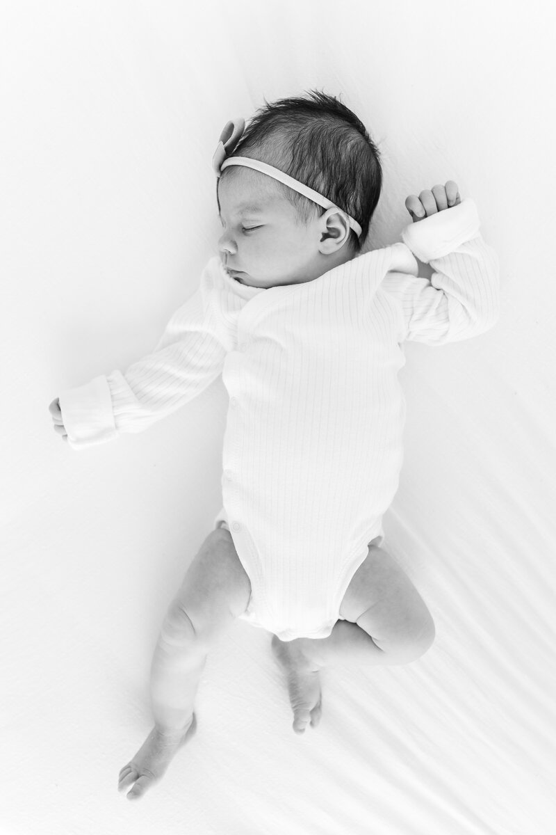 A black and white photo of a newborn baby girl sleeping on a bed by Washington DC Maternity photographer