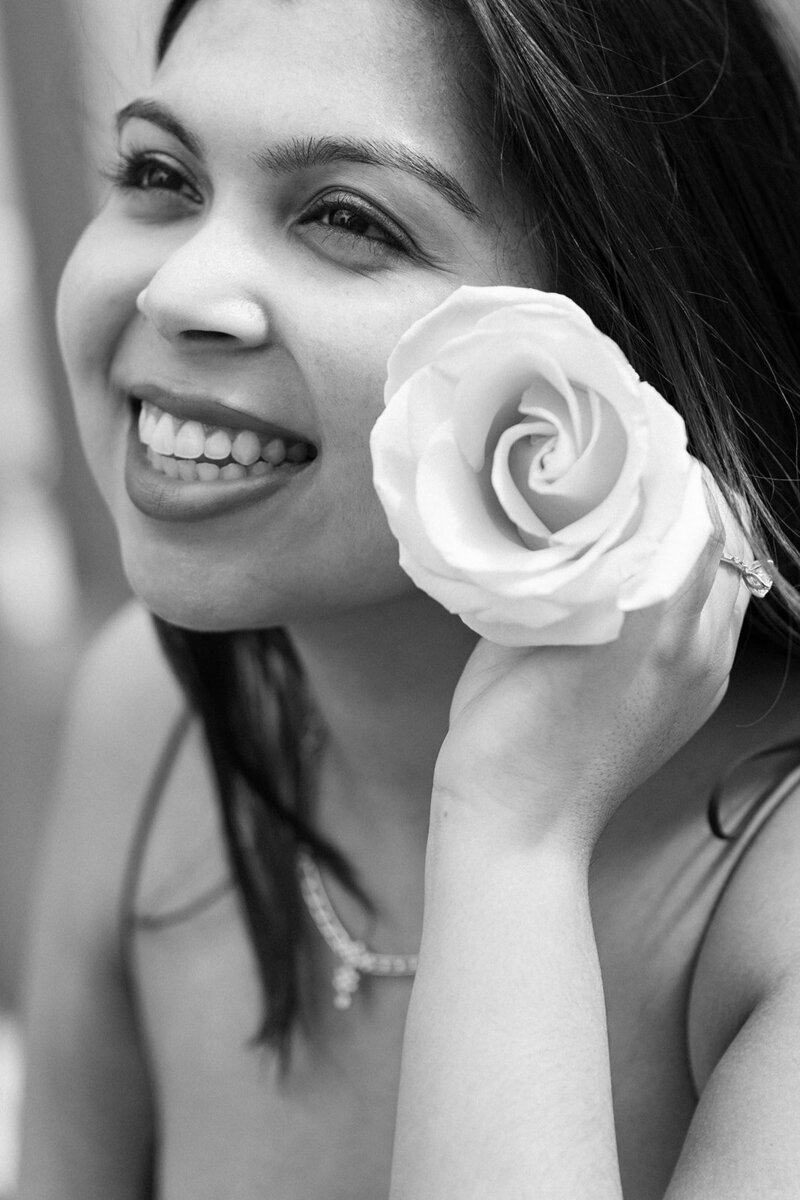 engaged bride holding a flower by her cheek