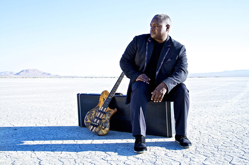 Music artist portrait Mitchell Coleman Jr sitting on guitar case in desert guitar leaning beside him