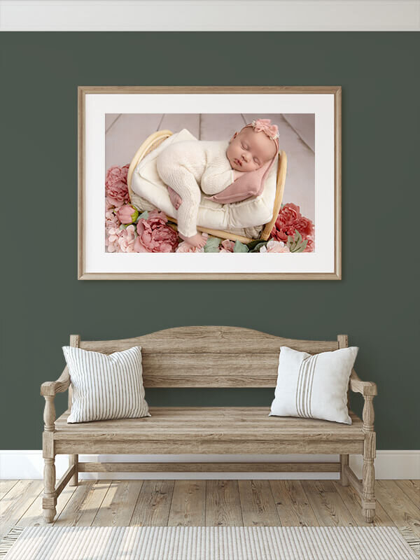 Framed photo of baby girl sleeping on a bed with flowers.