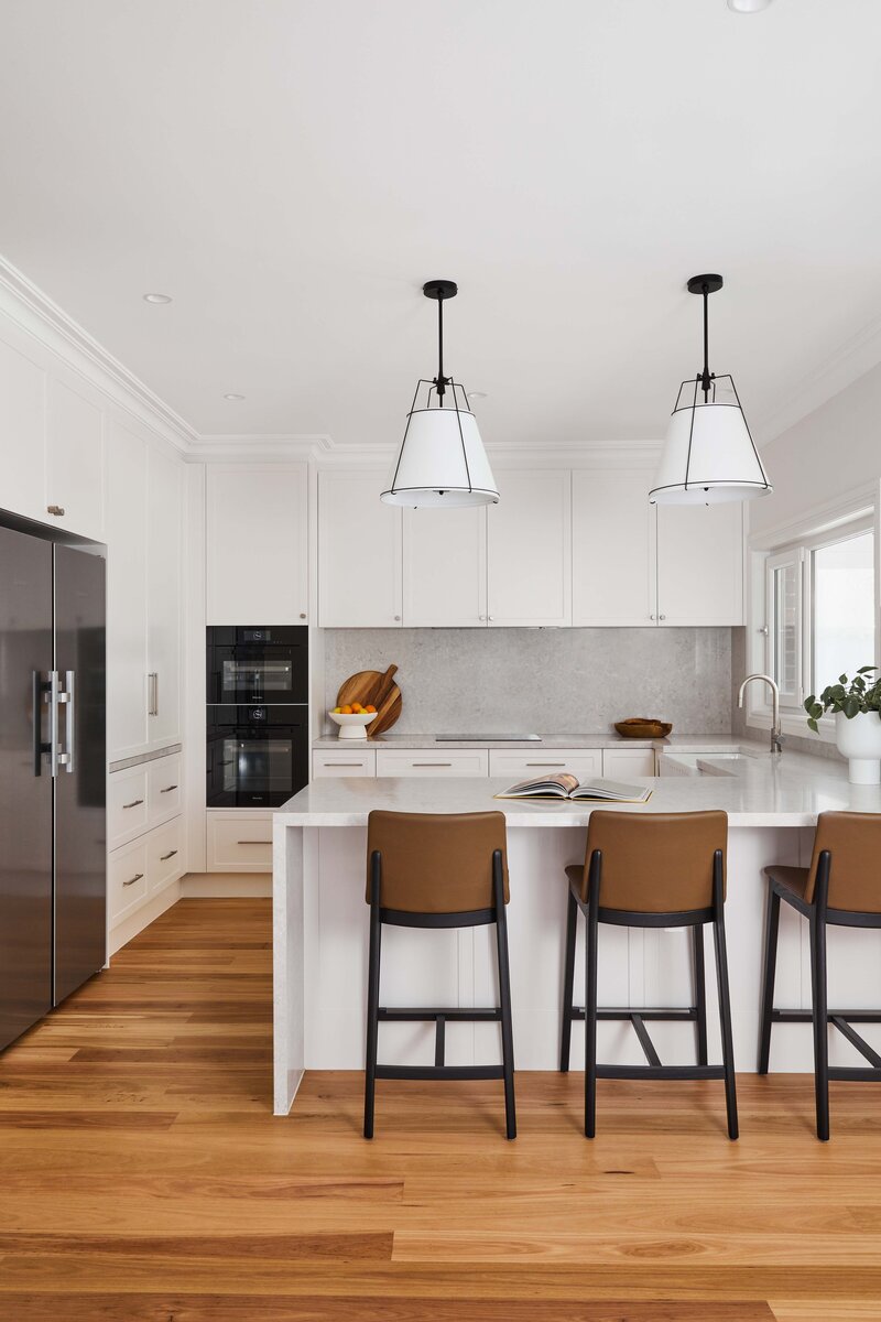 Renovated kitchen with white cabinetry and pendant lights | client testimonial interior design