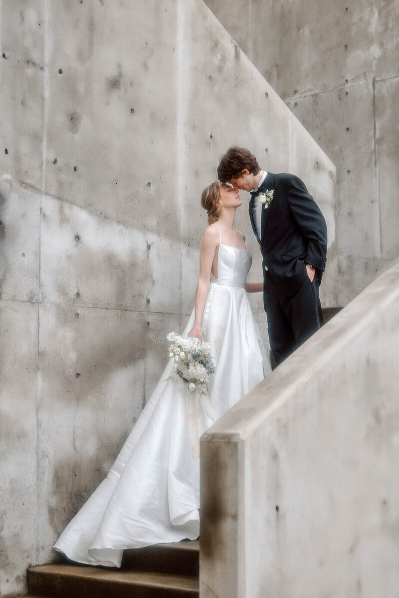 editorial bride and groom kiss on concrete staircase