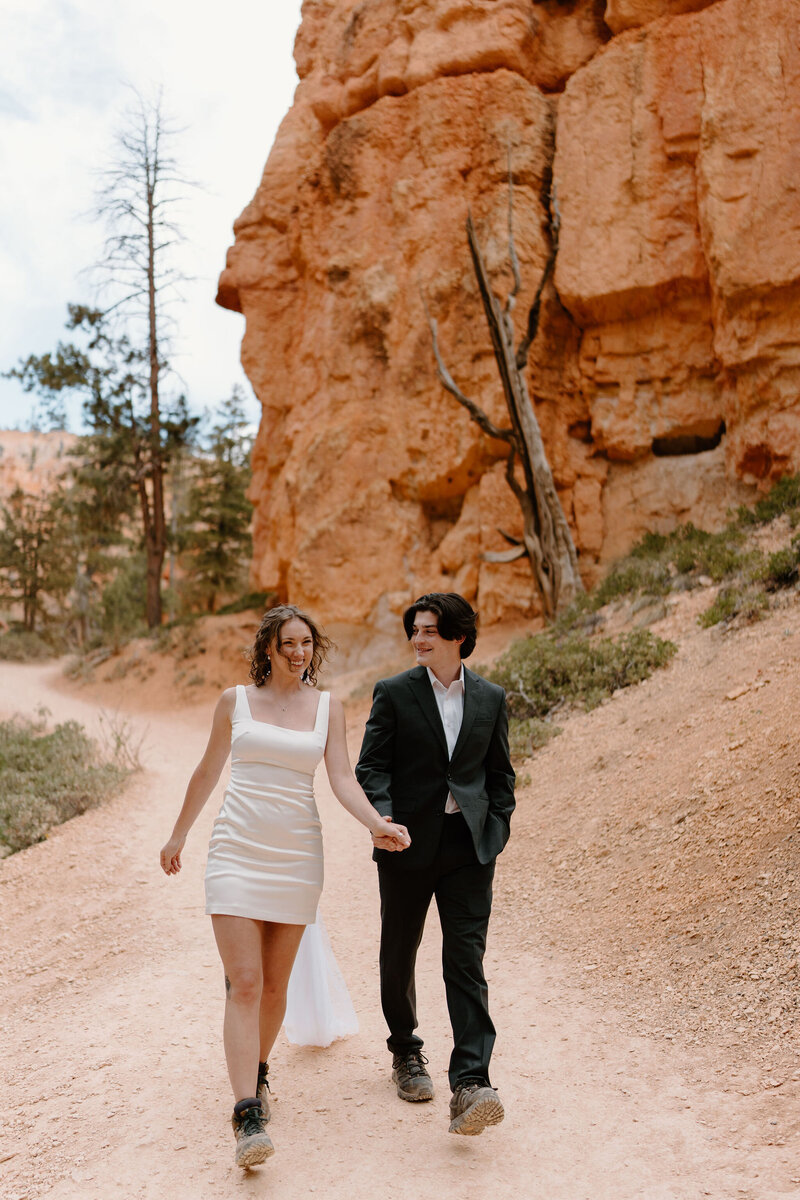 Bride (in short white dress) and Groom (in black suit), wearing hiking boots for their desert elopement