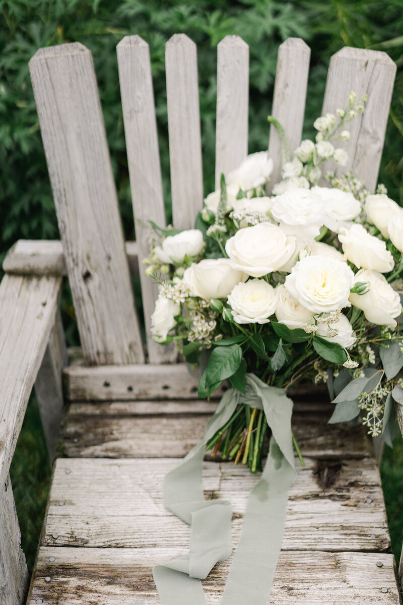 white and green wedding bouquet on wooden bench