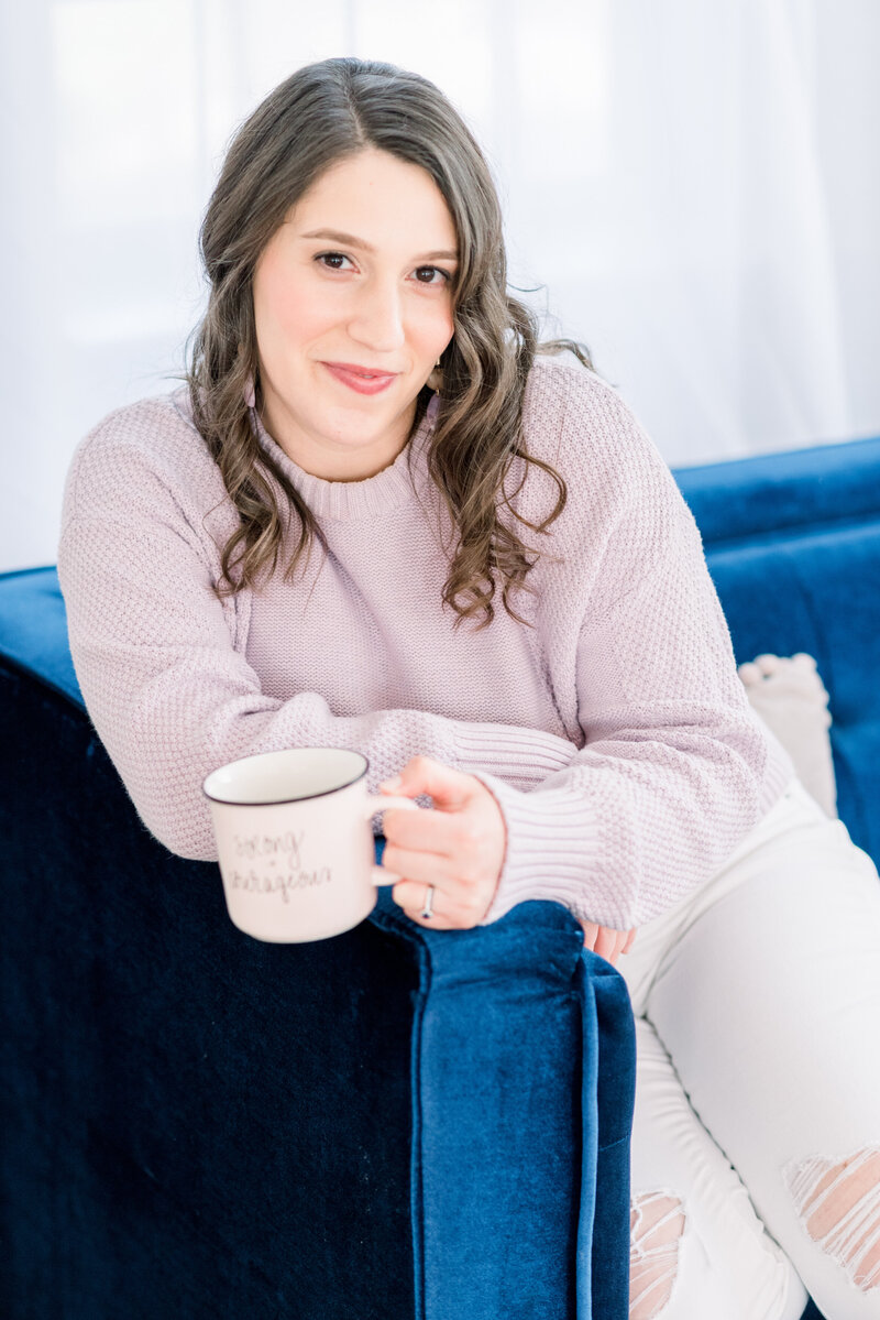 Isabel Kateman on a deep blue couch holding a mug of coffee