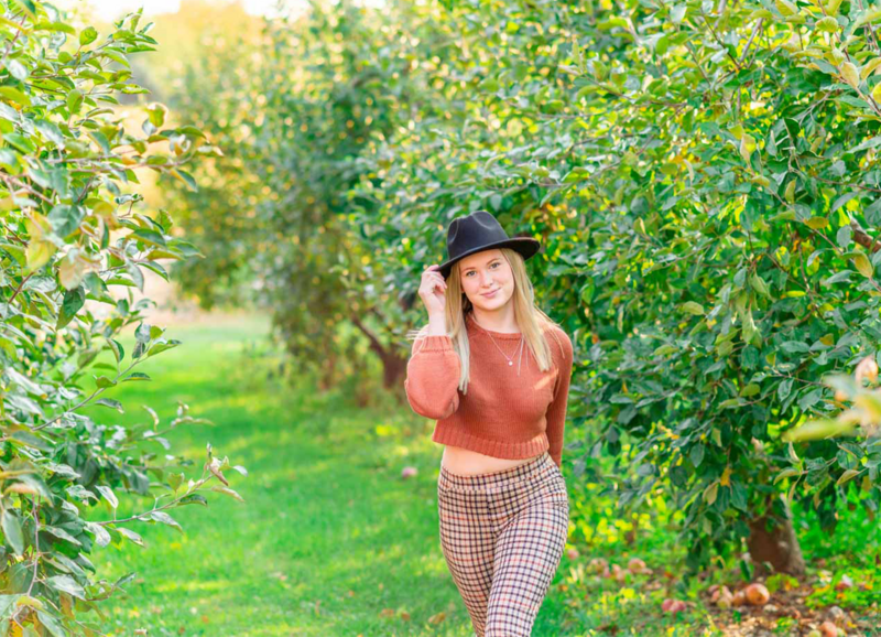 high school senior girl walking in apple orchard