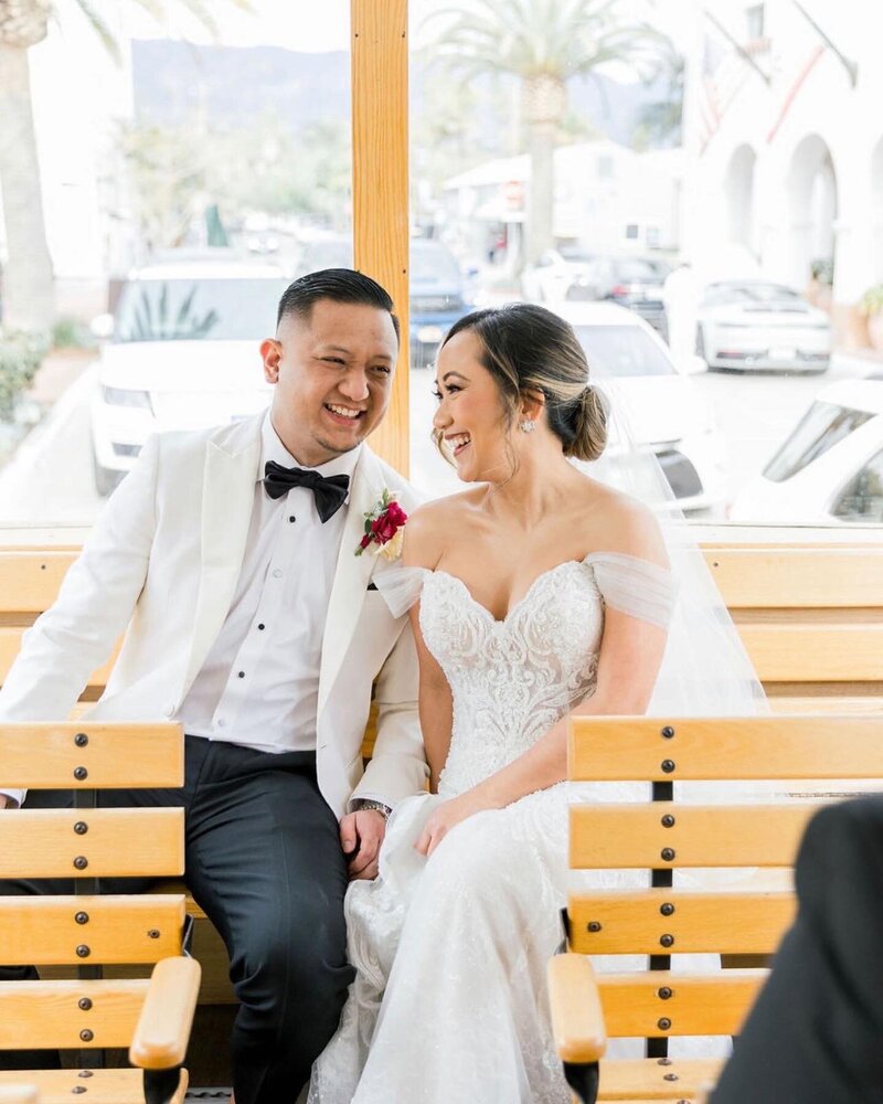 bride and groom share a laugh on a trolly