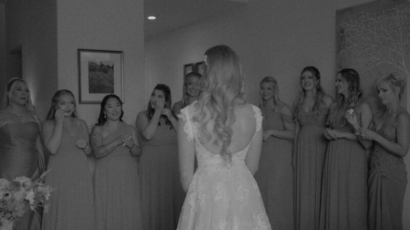 person in wedding dress standing in front of bridesmaids crying and celebrating over her