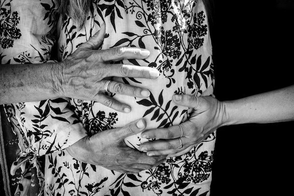 Family hands on pregnant belly
