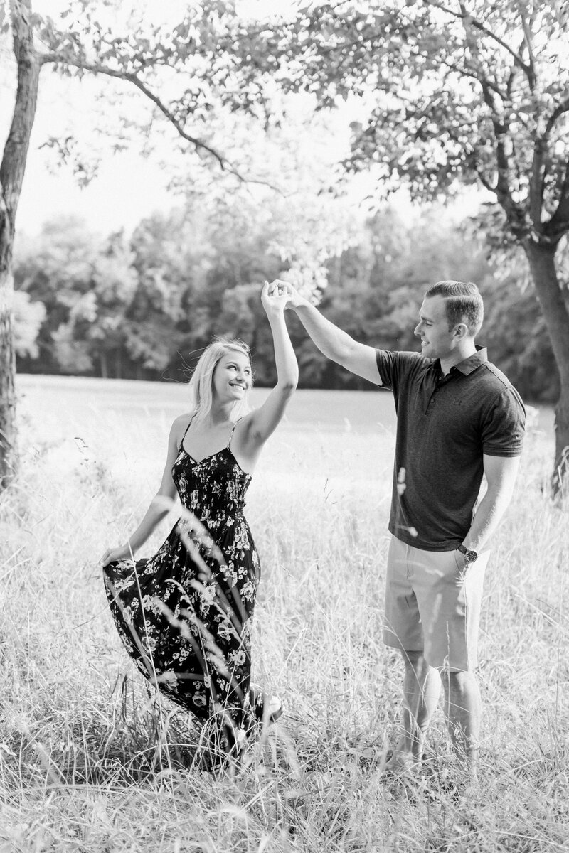 Engaged couple dancing in open field