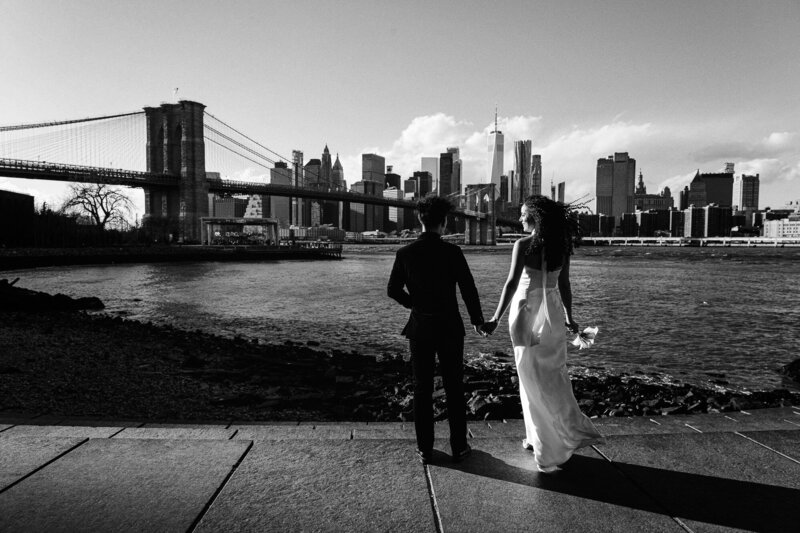 A wedding couple looking at the Brooklyn Bridhe and Lower Manhattan from Brooklyn.