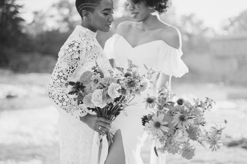Two brides standing together as they both hold bouquets of flowers.
