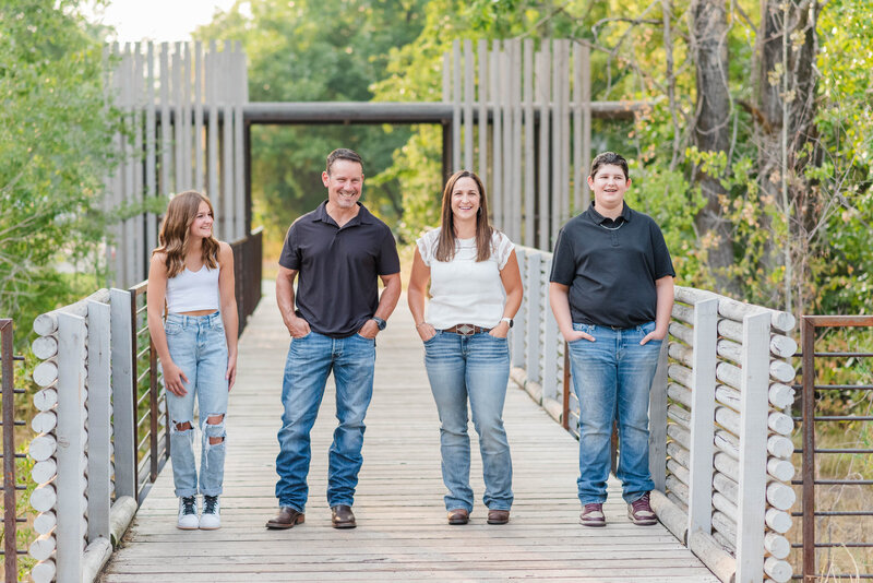 A family laughs together while posing on a bridge in a park in Bozeman, Montana by Laramee Love Photography