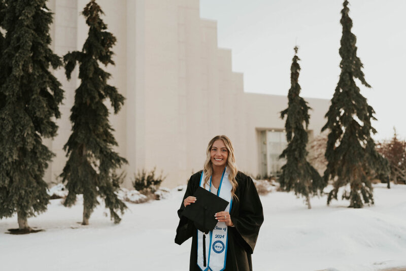 A BYU-Idaho graduate posing outside of the John Taylor building on campus