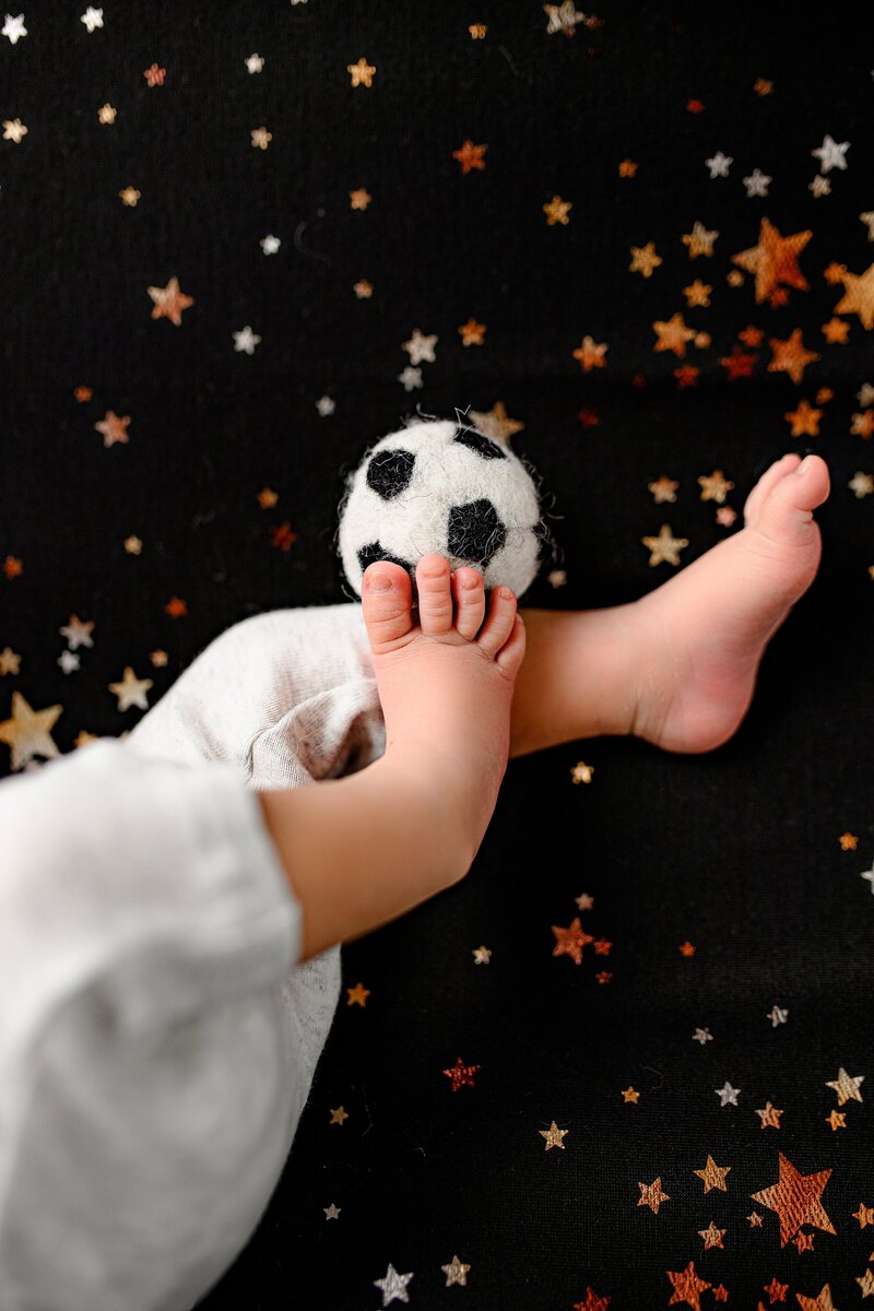 photo of a newborns feet  kicking a soccer ball