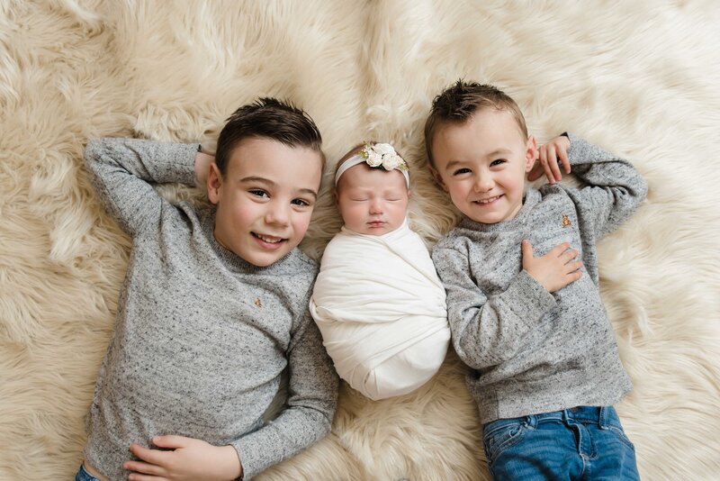 older brothers lie down with newborn baby sister in between  Baby Family Photographer Pittsburgh