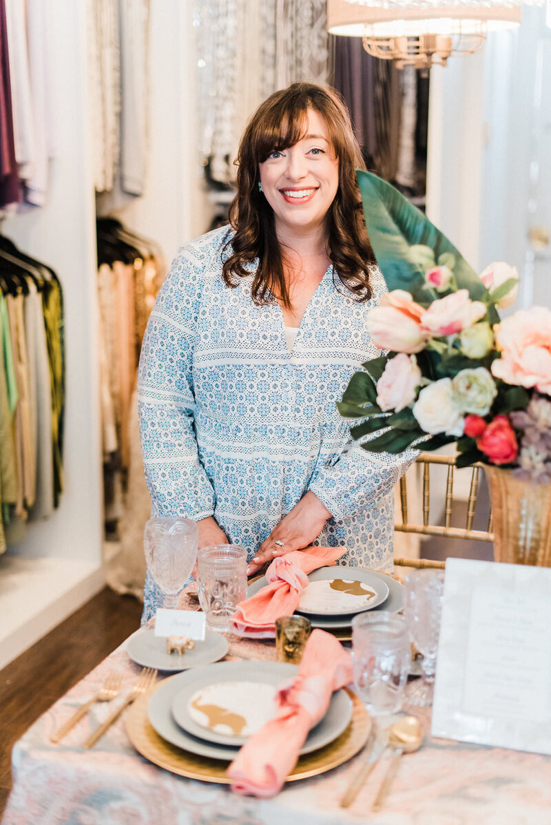 Moxie Bright Events founder, Renee Dalo, smiles while arranging a wedding tablescape