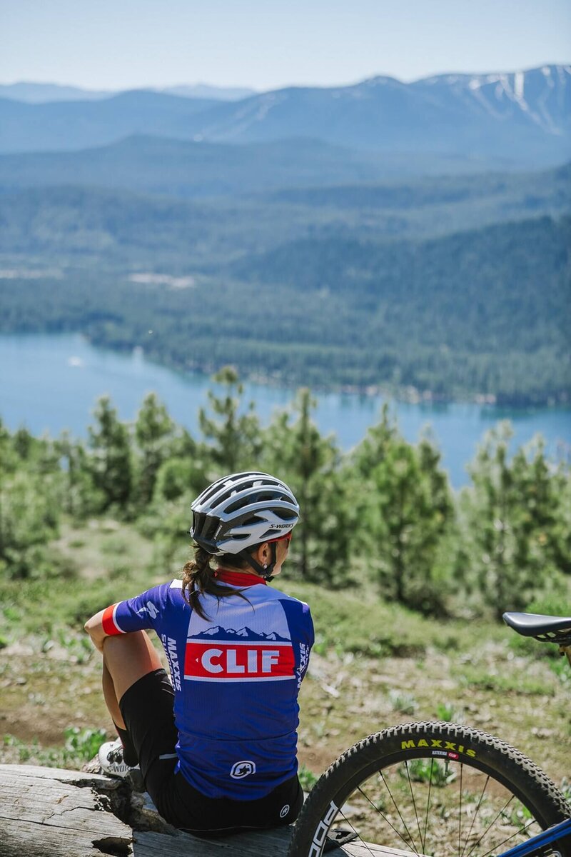 Branding session for mountain bike woman athlete sitting enjoying her Clif bar looking towards Donner Lake