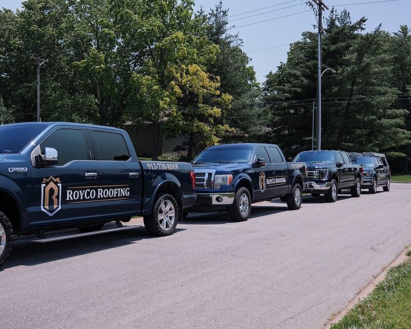 A line up of three Royco Roofing trucks outside a Kansas City home getting a new roof