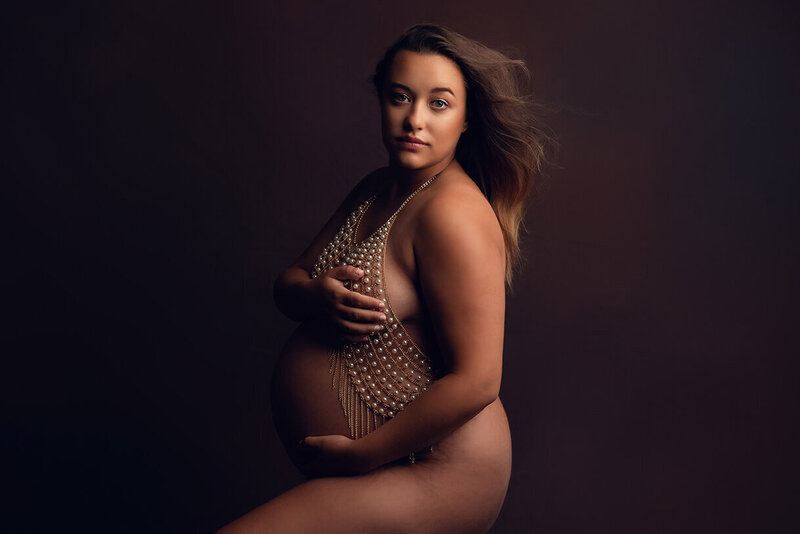 a gorgeous pregnant woman wearing body jewelry holding her bump