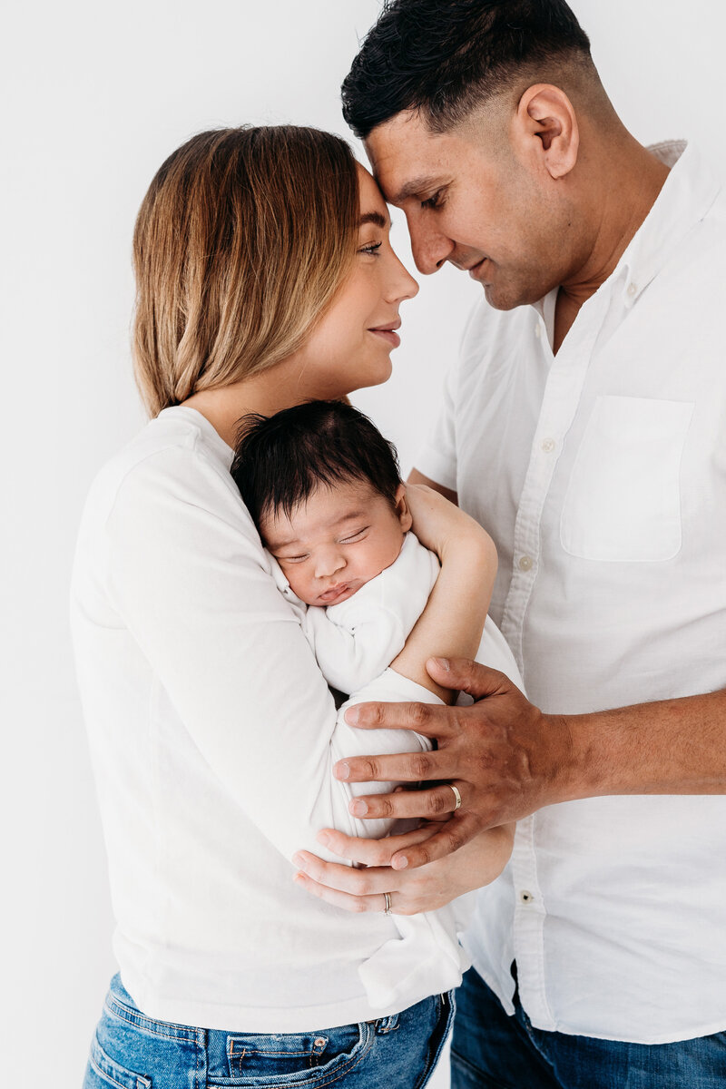 Happy new parents holding their sleeping baby on a photoshoot in Cheshire