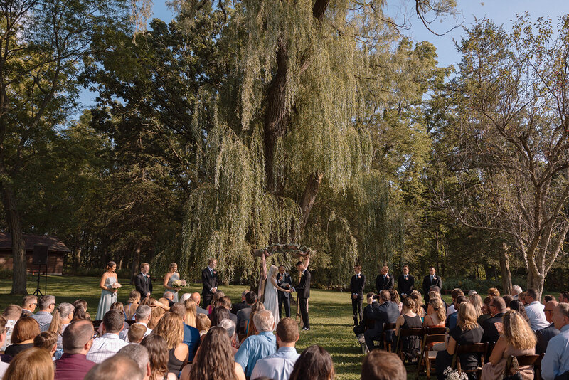 outdoor wedding ceremony under the willow tree at barnwood events, a country side wedding venue in madison, winconsin.
