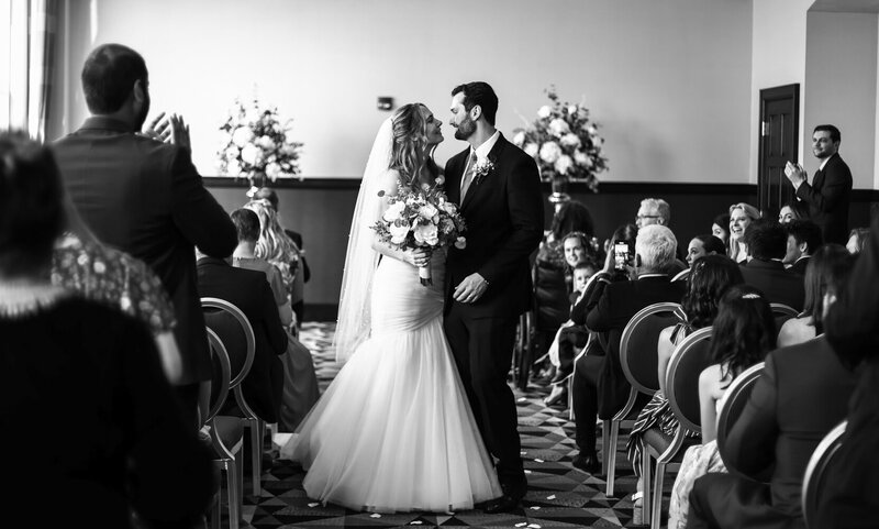 Bride and groom pause to look lovingly at each other during their recessional at the end of their Sheraton Erie Bayfront wedding ceremony