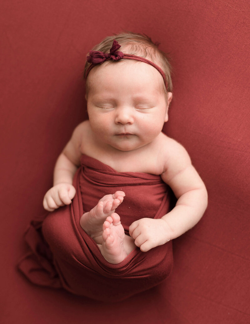 Baby girl wrapped in burgundy fabric