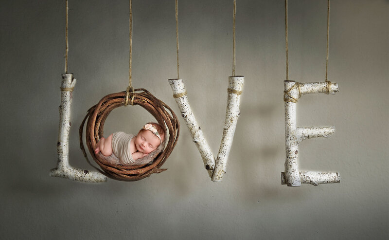 newborn girl posed on a wooden love sign