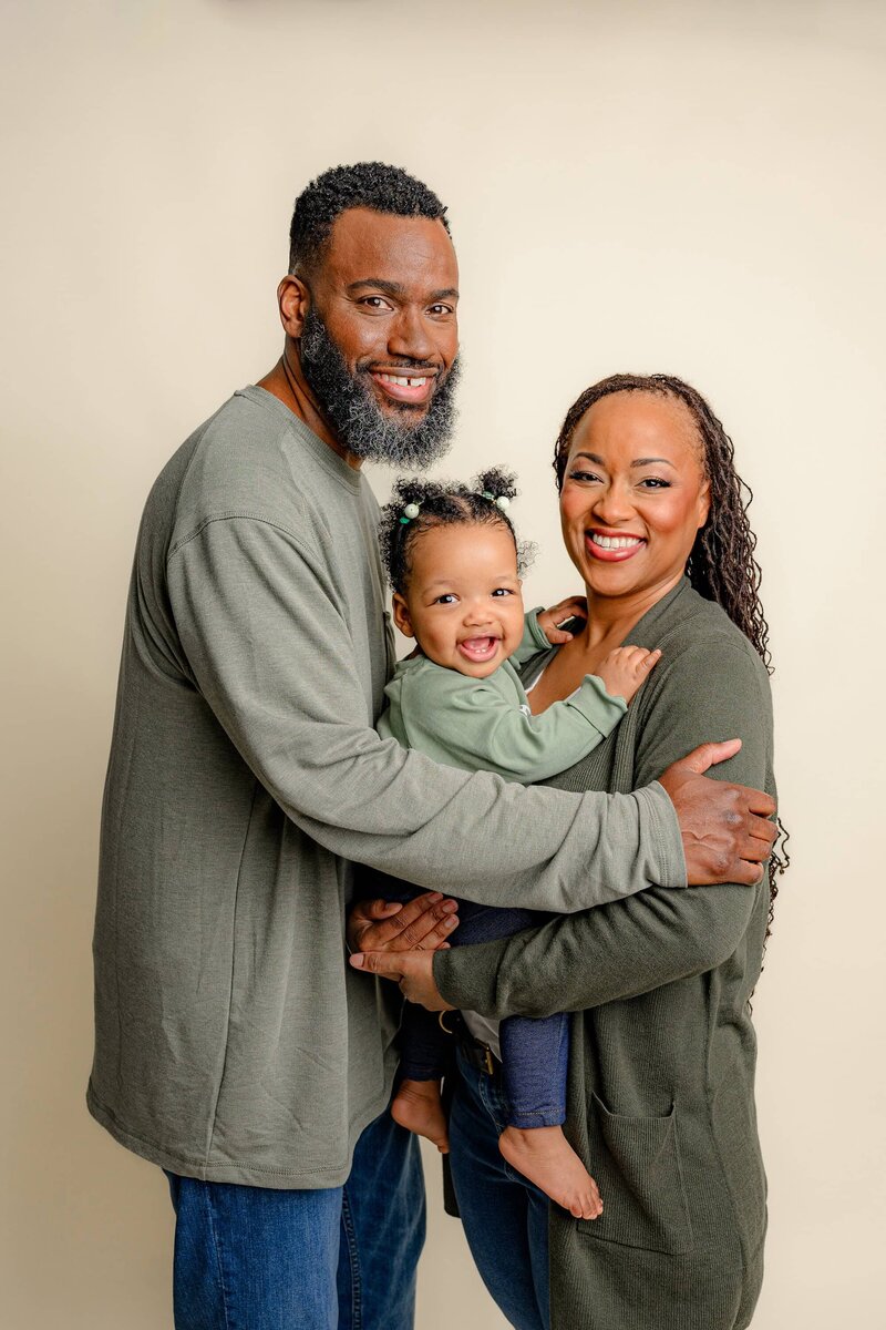 family of three dressed in greens snuggled together for their little girls birthday