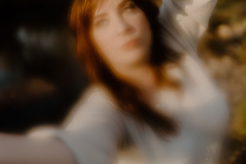 blurred photo of Annie woman reaching toward camera lens looking up with water reflection background